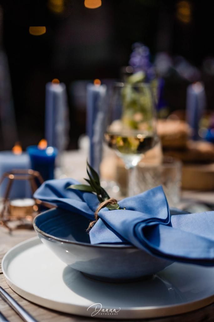 Gedekte tafel voor diner met blauw servet en bord en onderbord