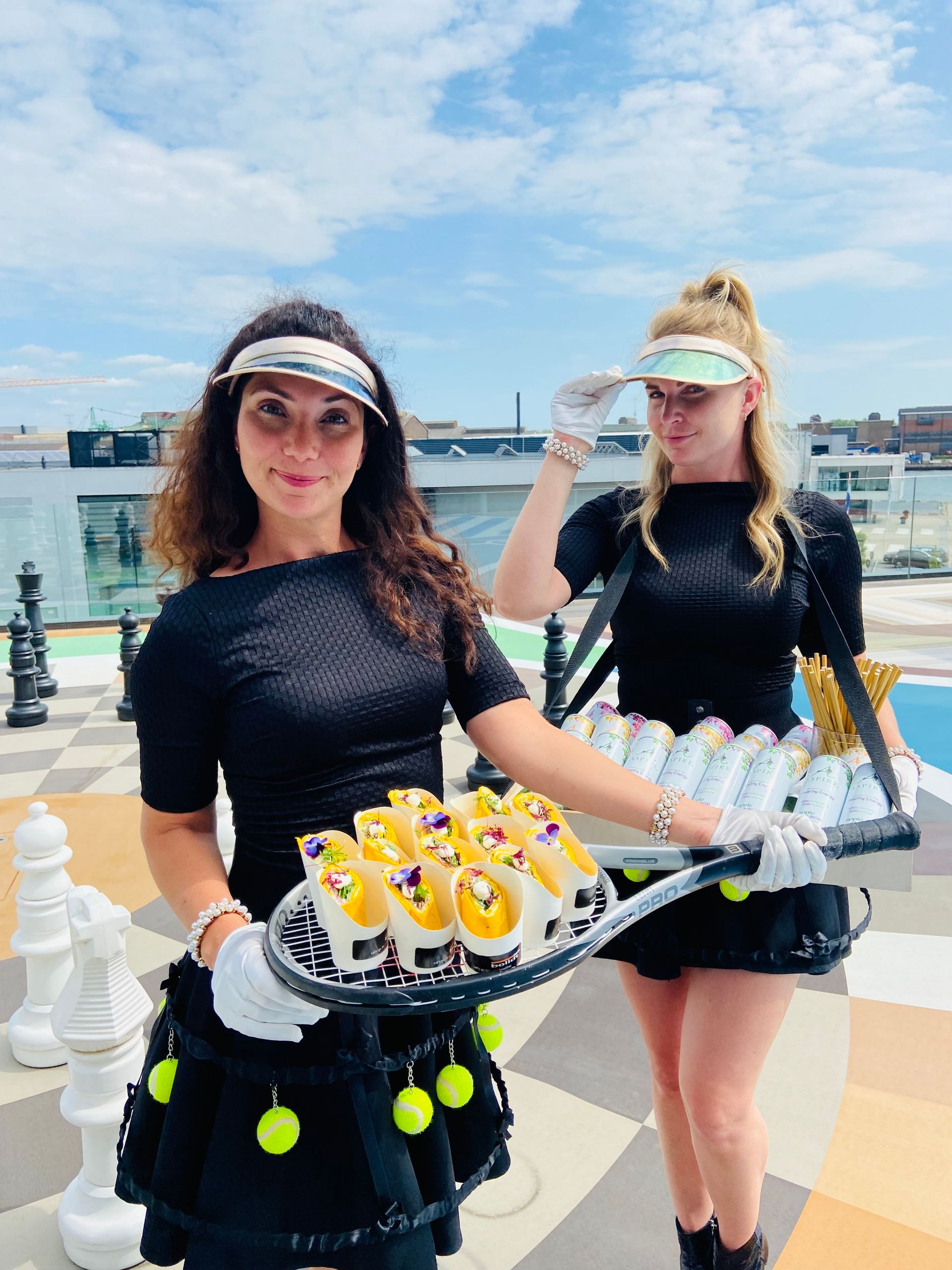 Twee vrouwelijke bediendes die hapjes uitdelen op bedrijfsfeest