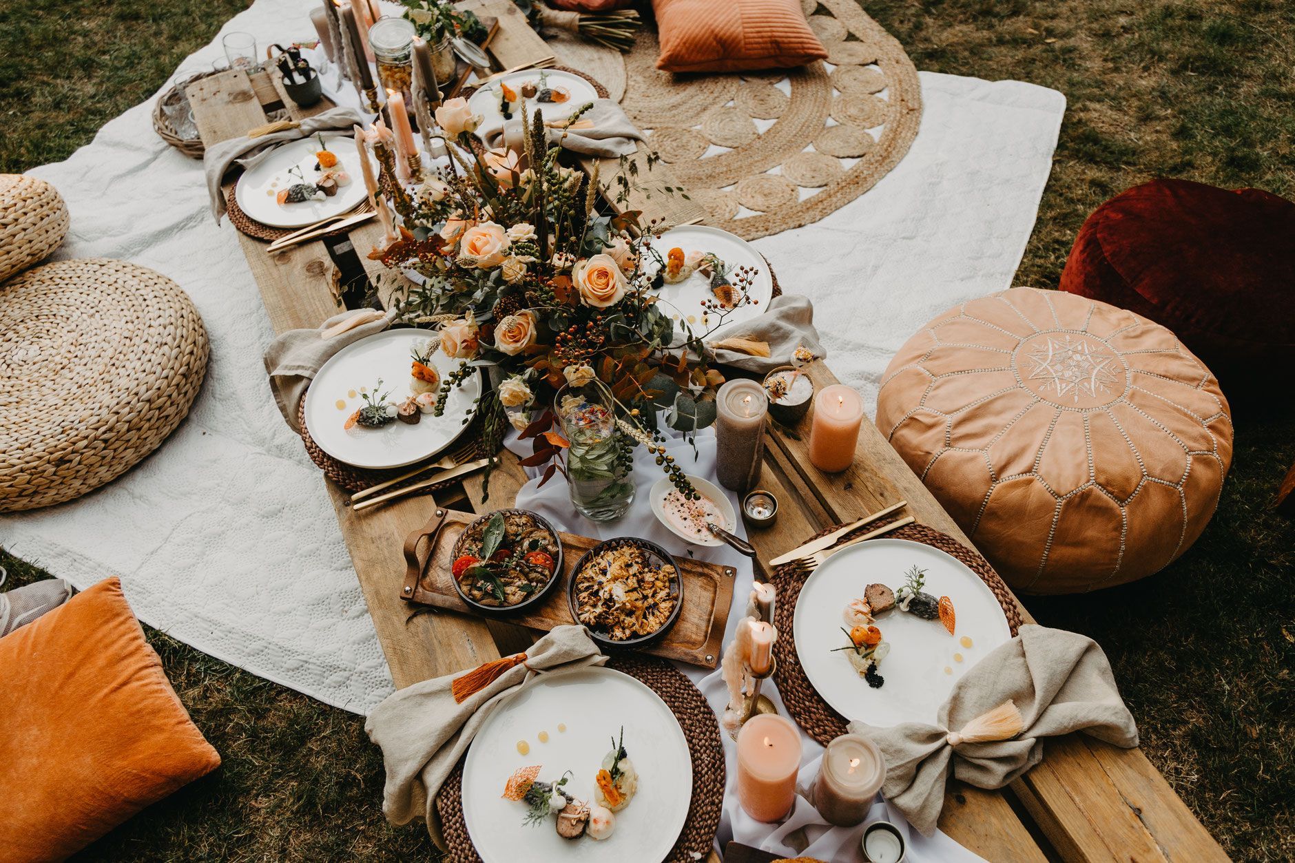 Kussentjes en wit kleed met daarop witte borden en mooi eten in bohemain stijl