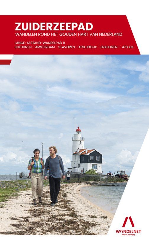 Twee mensen lopen over een pad met een vuurtoren op de achtergrond, ter promotie van de wandelroute Zuiderzeepad.