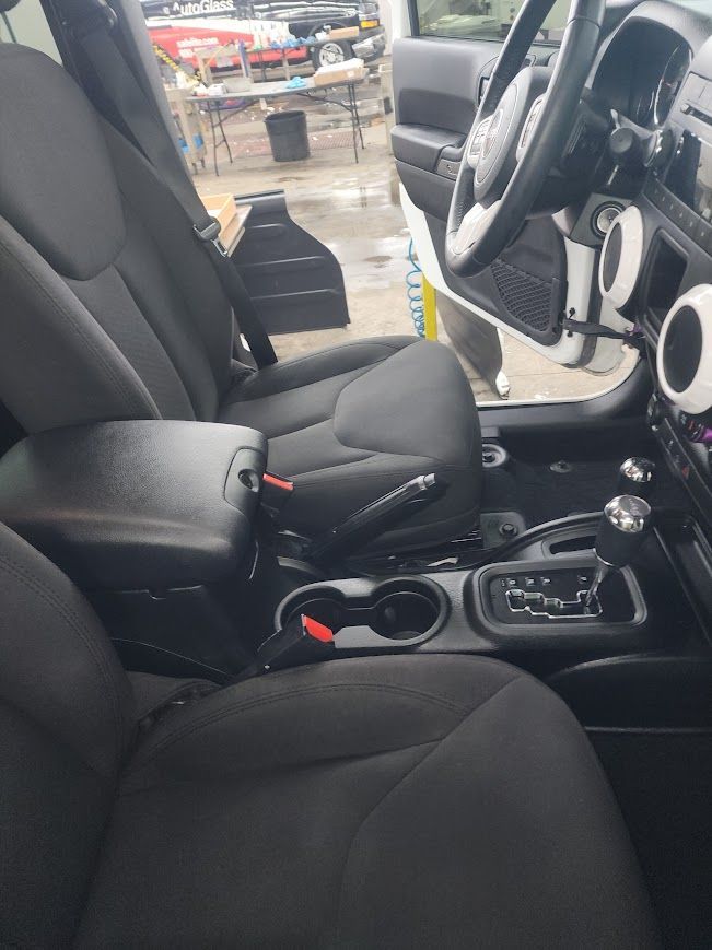 The interior of a jeep wrangler is shown with the door open.