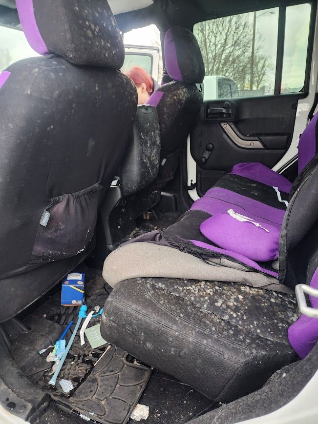The inside of a dirty car with purple seat covers.