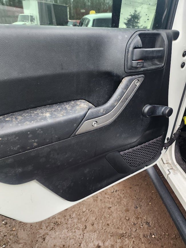 A close up of a dirty door handle on a white car.