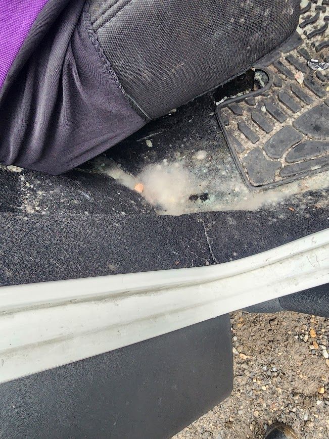 A person is sitting on a dirty scooter with a purple shirt on.