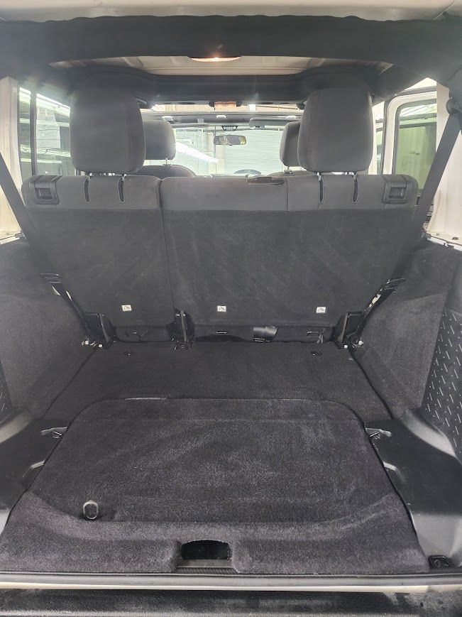The trunk of a jeep wrangler is open and empty.