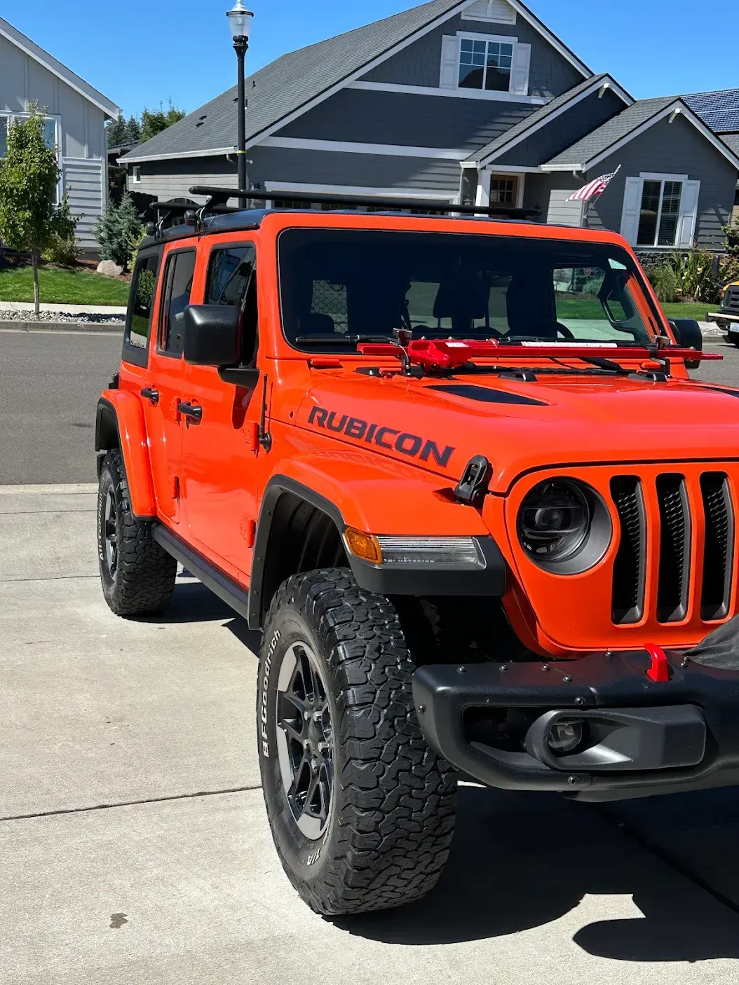 An orange jeep rubicon is parked in front of a house
