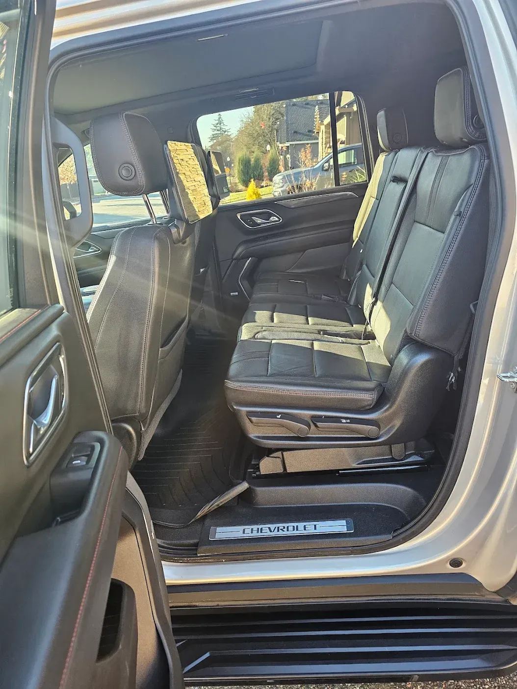 The back seat of a silver car with the door open.