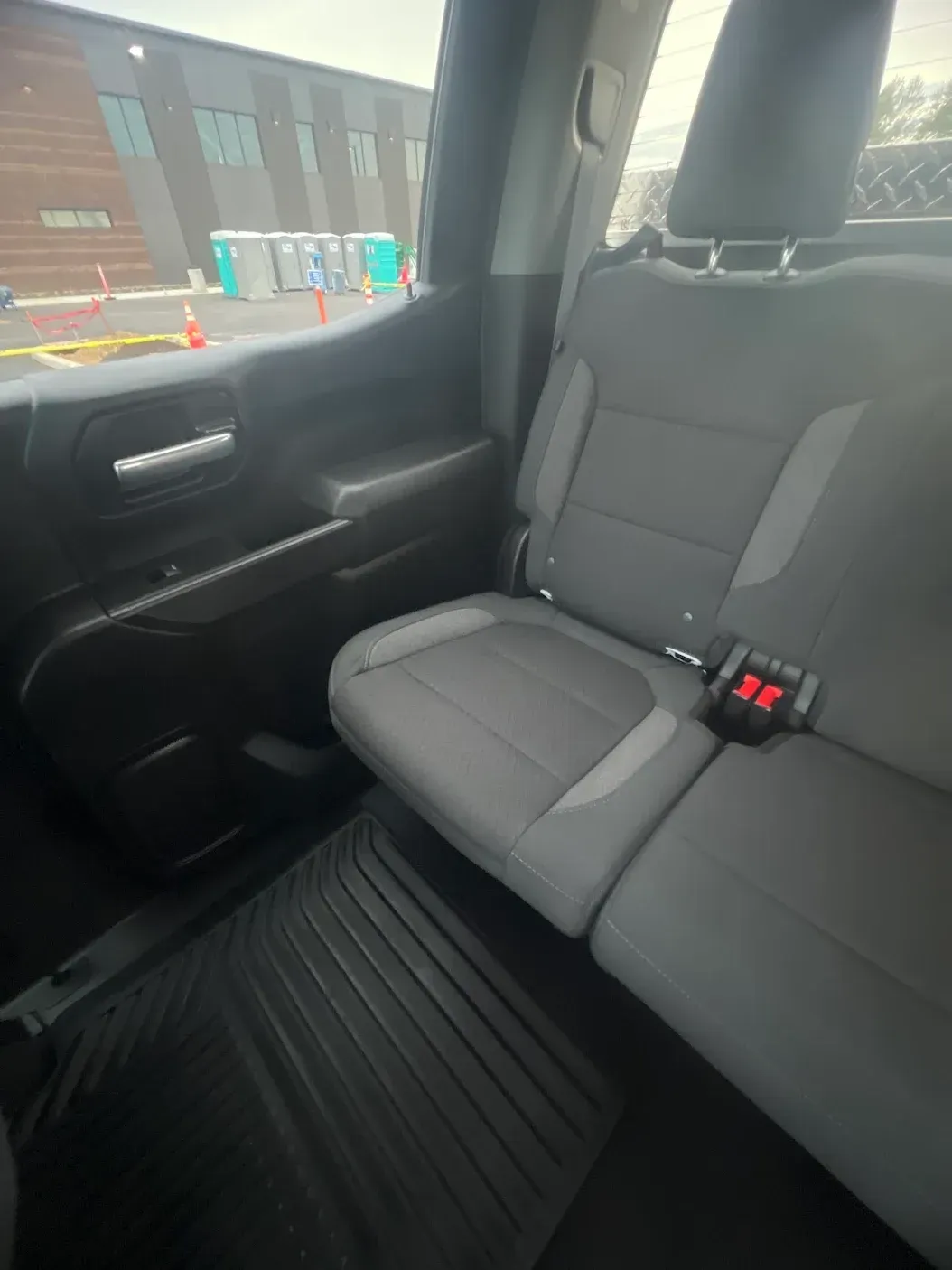 The back seat of a truck with a red button on the seat belt.