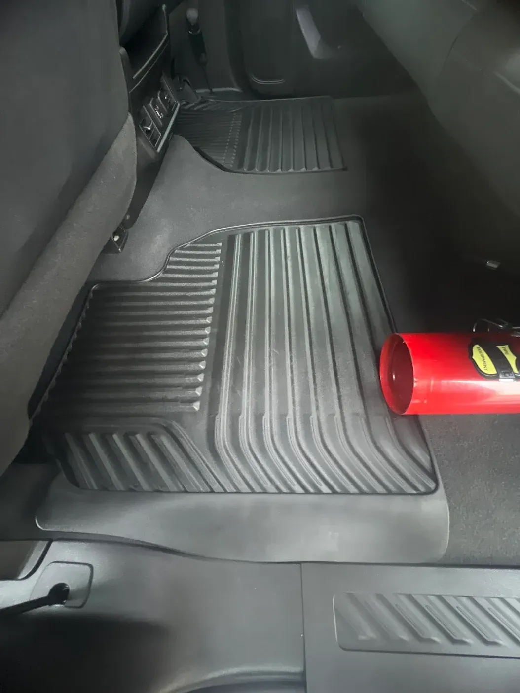 A red can of pringles sits on the floor of a car