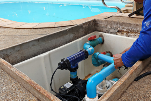 A man is working on a swimming pool pump.