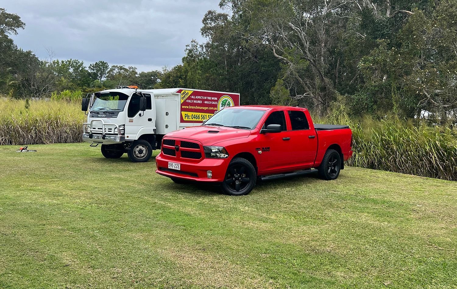 Red Dodge Ram Pickup Truck and White Truck Parked on Grass
