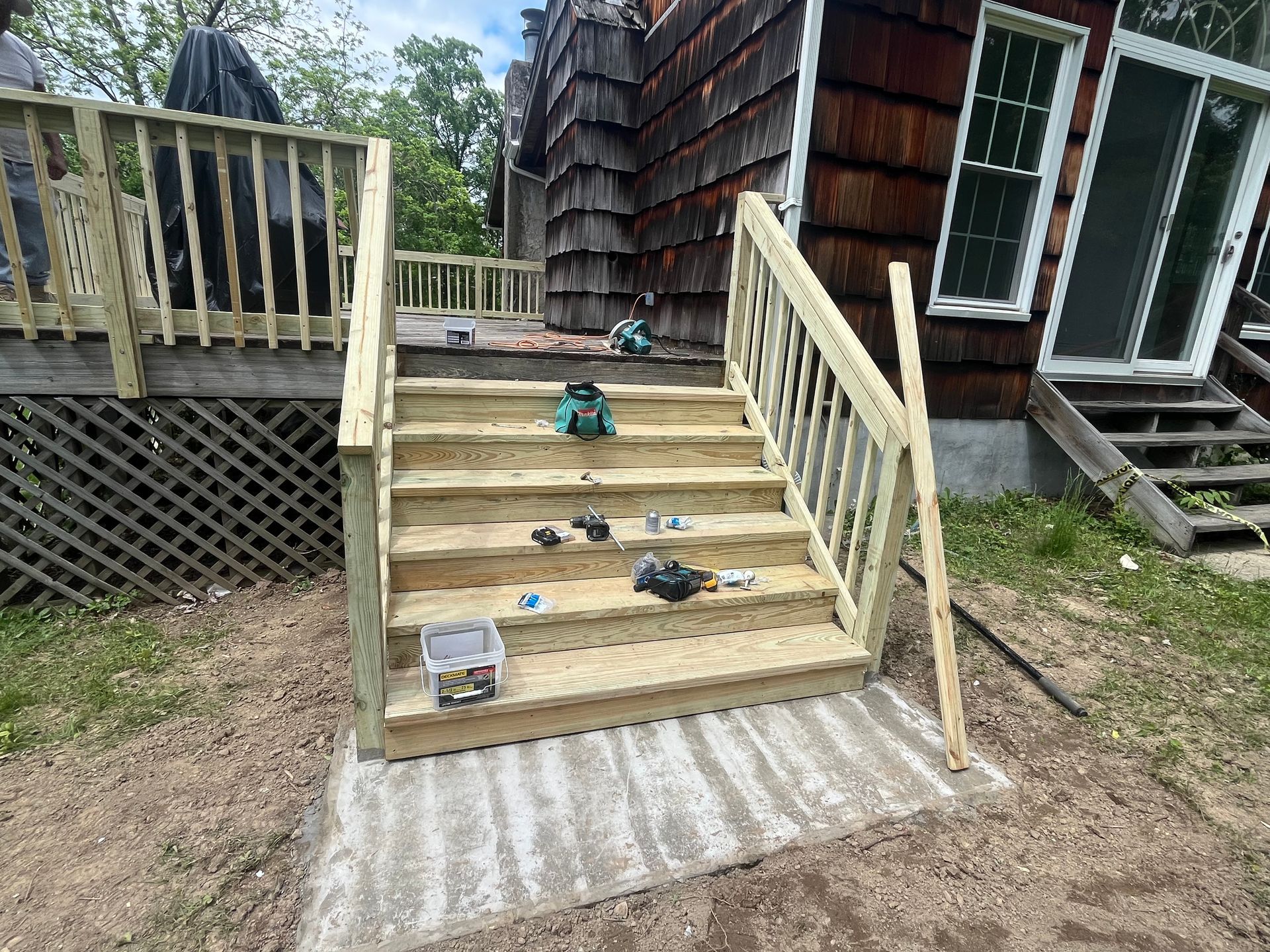 Newly constructed wooden outdoor stairs leading to a house with tools and debris scattered on the steps.