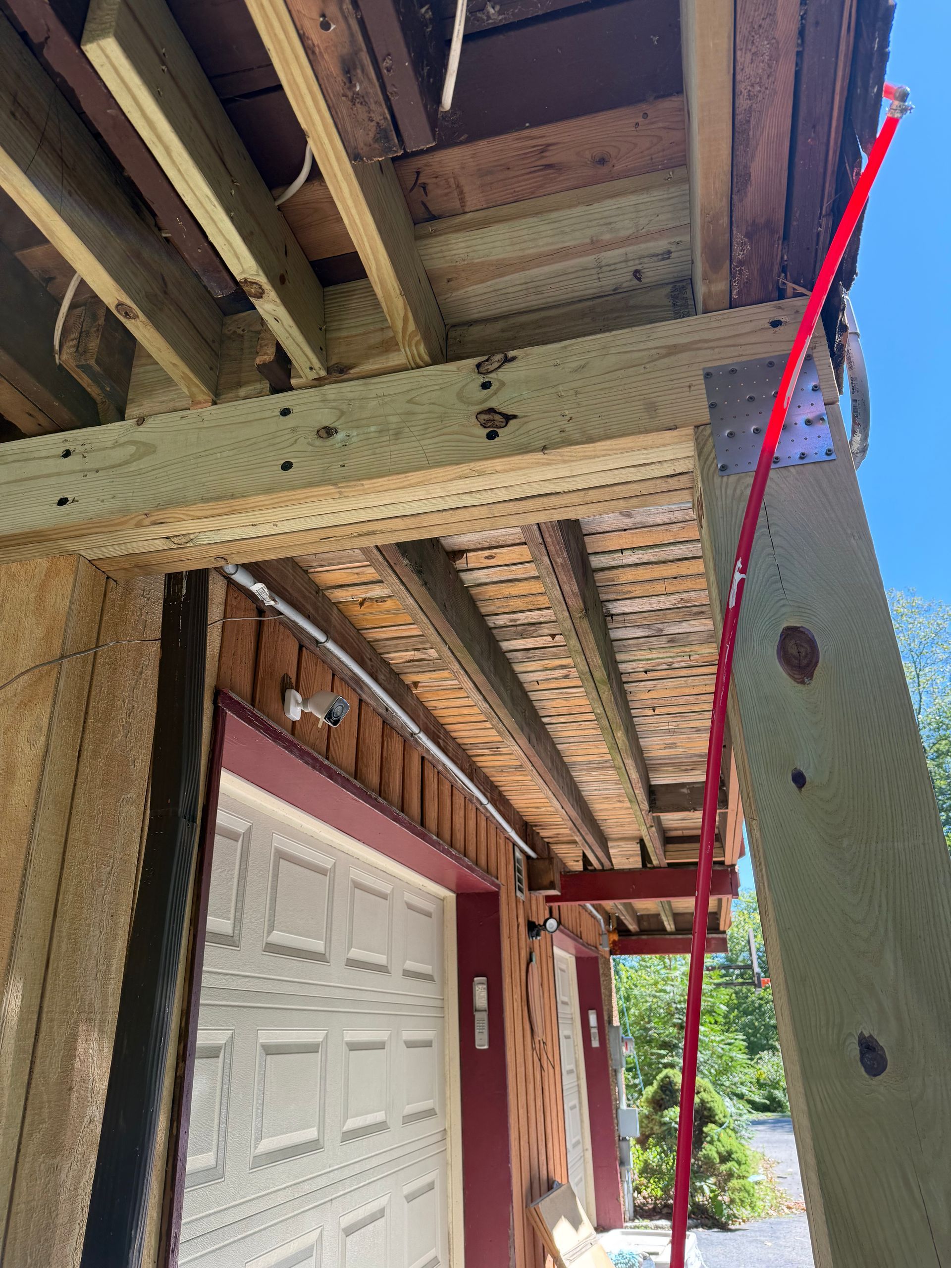 Garage exterior with red electrical wire running up a wooden post. Blue sky.