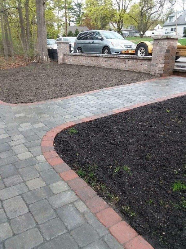 Stone pathway with a garden bed of mulch and plants next to a stone wall.