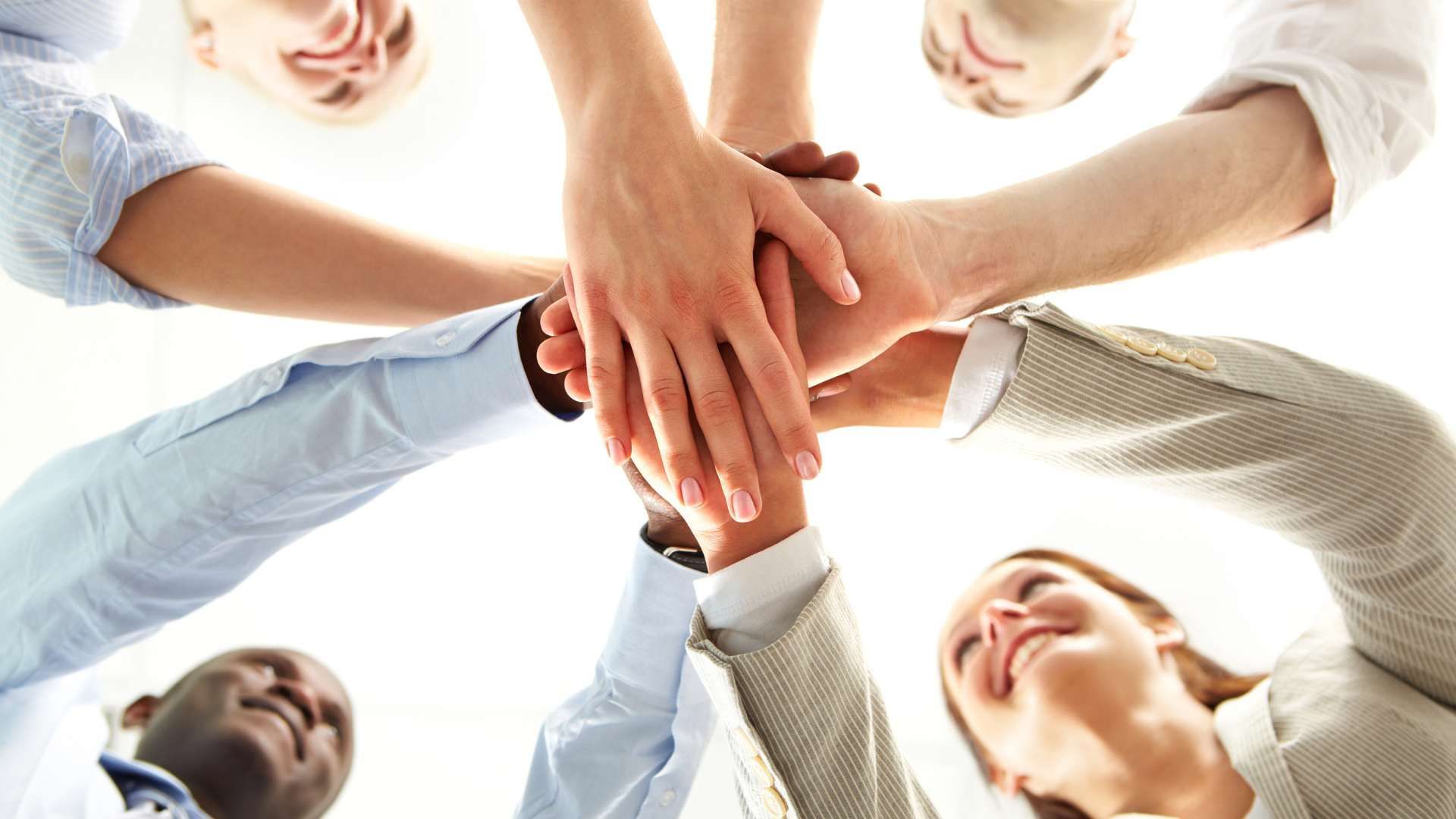 A group of people are putting their hands together in a circle.