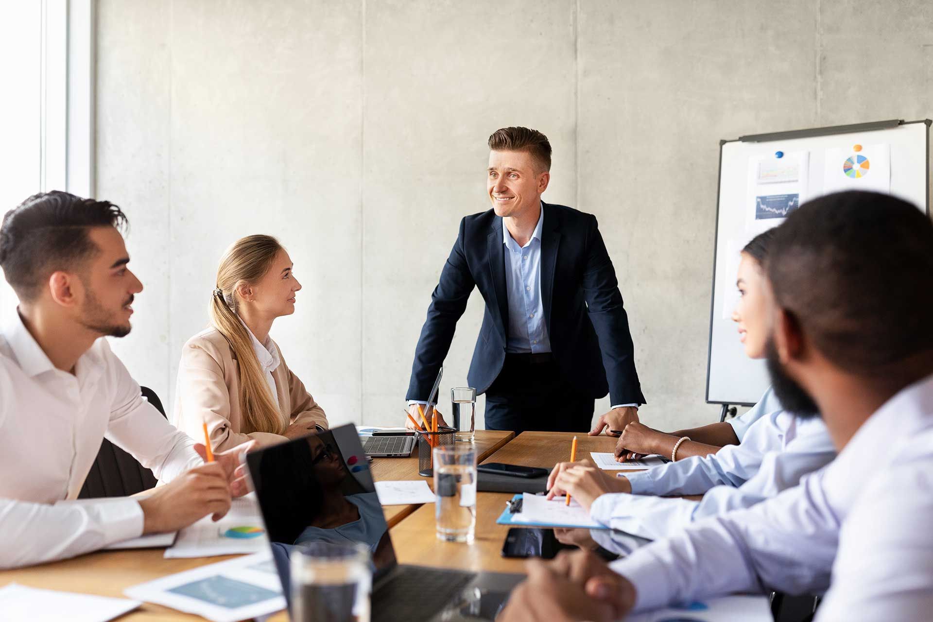 A man is giving a presentation to a group of people sitting around a table.