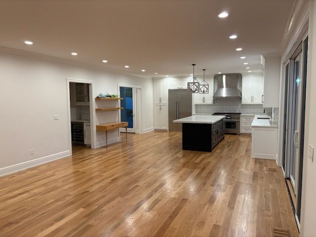 Spacious kitchen with wood floors, white cabinets, black island, stainless appliances, and recessed lighting.