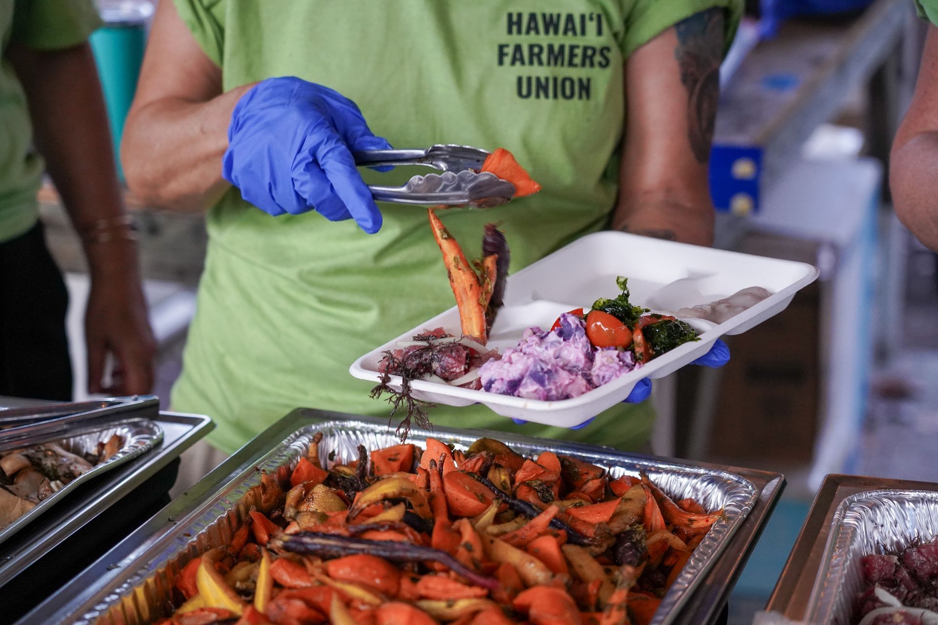 Vendor serving grilled lobster at a food stall, with trays of seafood and vegetables on display