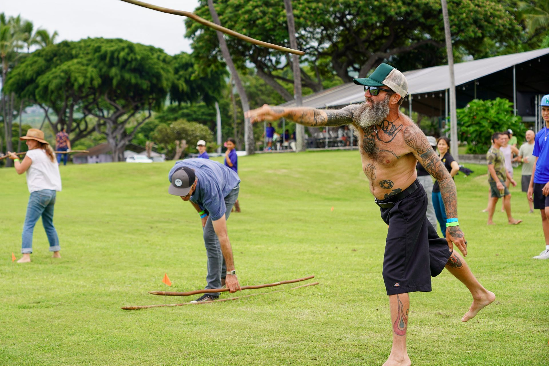 Outdoor lawn game with two people balancing on stilts while others watch in a park