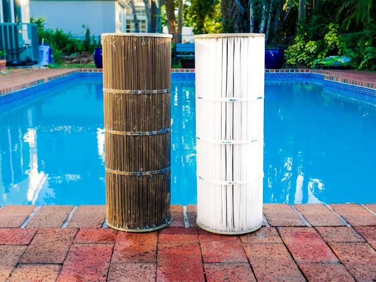 Two Pool Filters Are Sitting Next to Each Other on the Edge of a Swimming Pool — Whitsunday Pool Service in Cannonvale, QLD