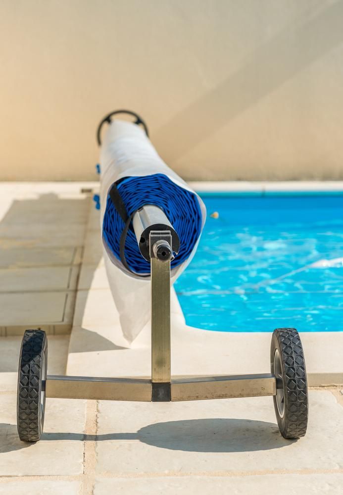 A Roll of Solar Blankets is Sitting on a Cart Next to a Swimming Pool — Whitsunday Pool Service in Airlie Beach, QLD