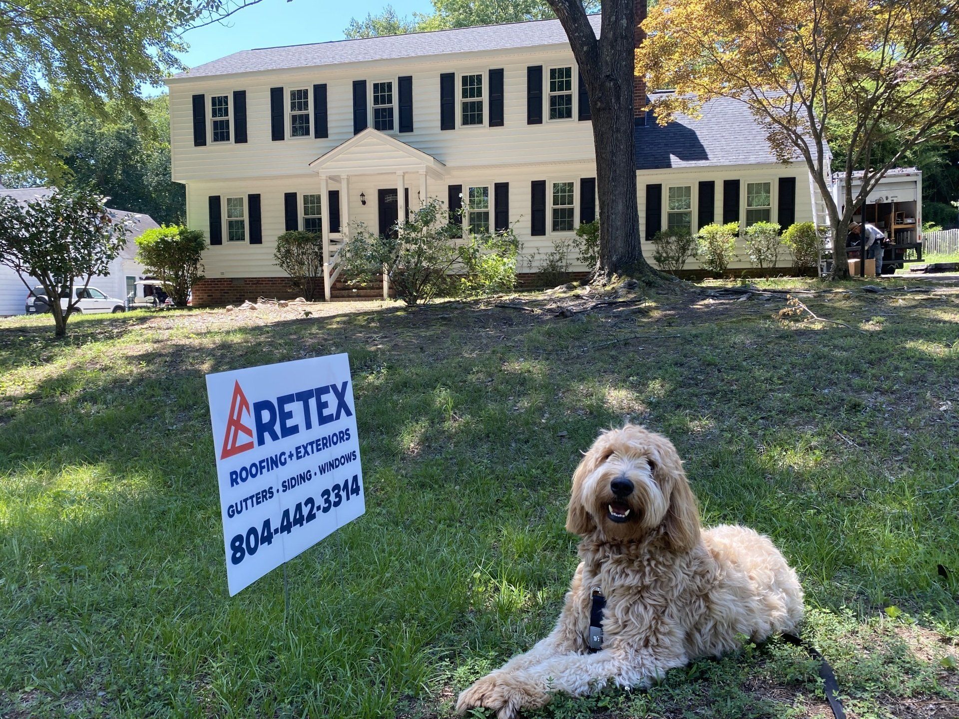 Image of RETEX's Albus Lewis with yard sign in front of home after RETEX replaced the roof, siding, windows and gutters. 