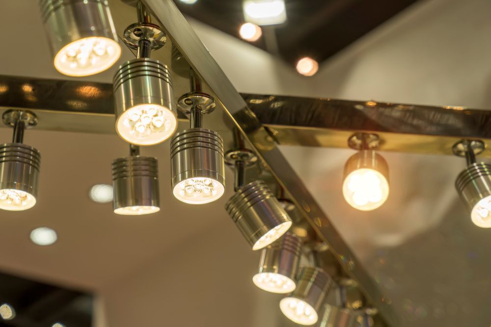 Row of hanging spotlights and warm bulbs illuminating a mirrored ceiling