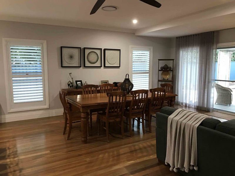 Dining Room With Wooden Table, Chairs, And Shutters — Winning Blinds in Cardiff, NSW