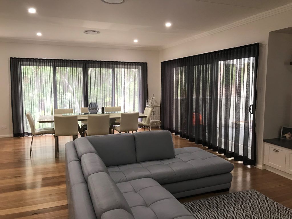 A Living Room with A Couch, Table, Chairs, and Sliding Glass Doors — Winning Blinds in Newcastle, NSW