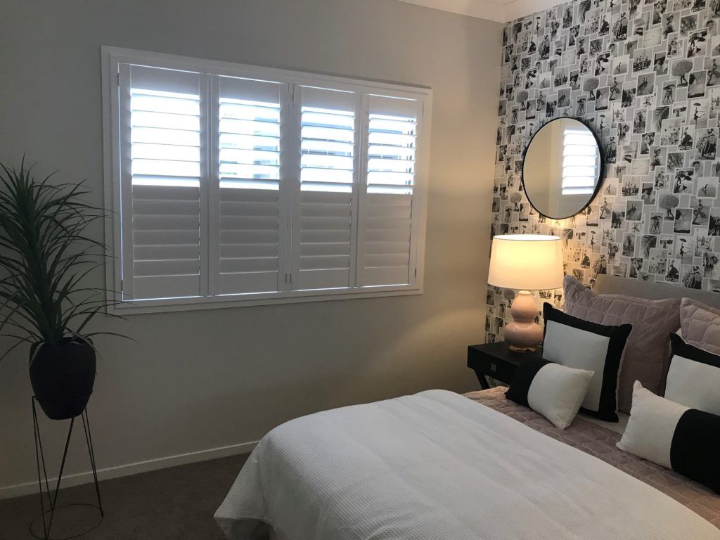 A Bedroom with A Bed, Nightstand, Mirror and Shutters — Winning Blinds in Cardiff, NSW
