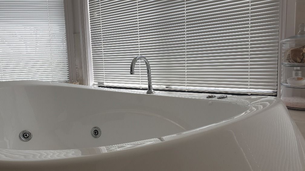 A bath tab with Aluminium venetians blonds behind it— Winning Blinds in Cardiff, NSW