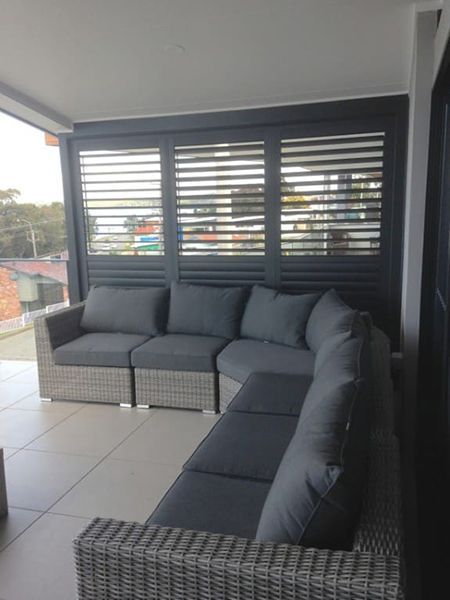 Lounge Seating On A Balcony With Gray Cushions, And Dark Shutters — Winning Blinds in Cardiff, NSW