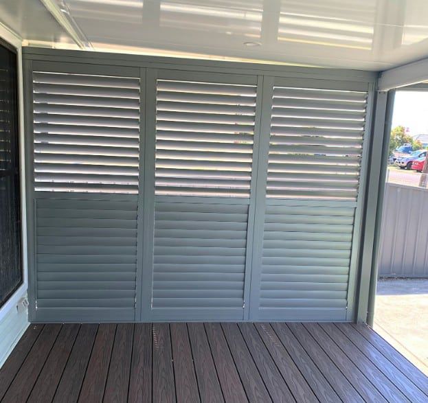 Gray Shutter-style Doors On A Wooden Deck — Winning Blinds in Cardiff, NSW