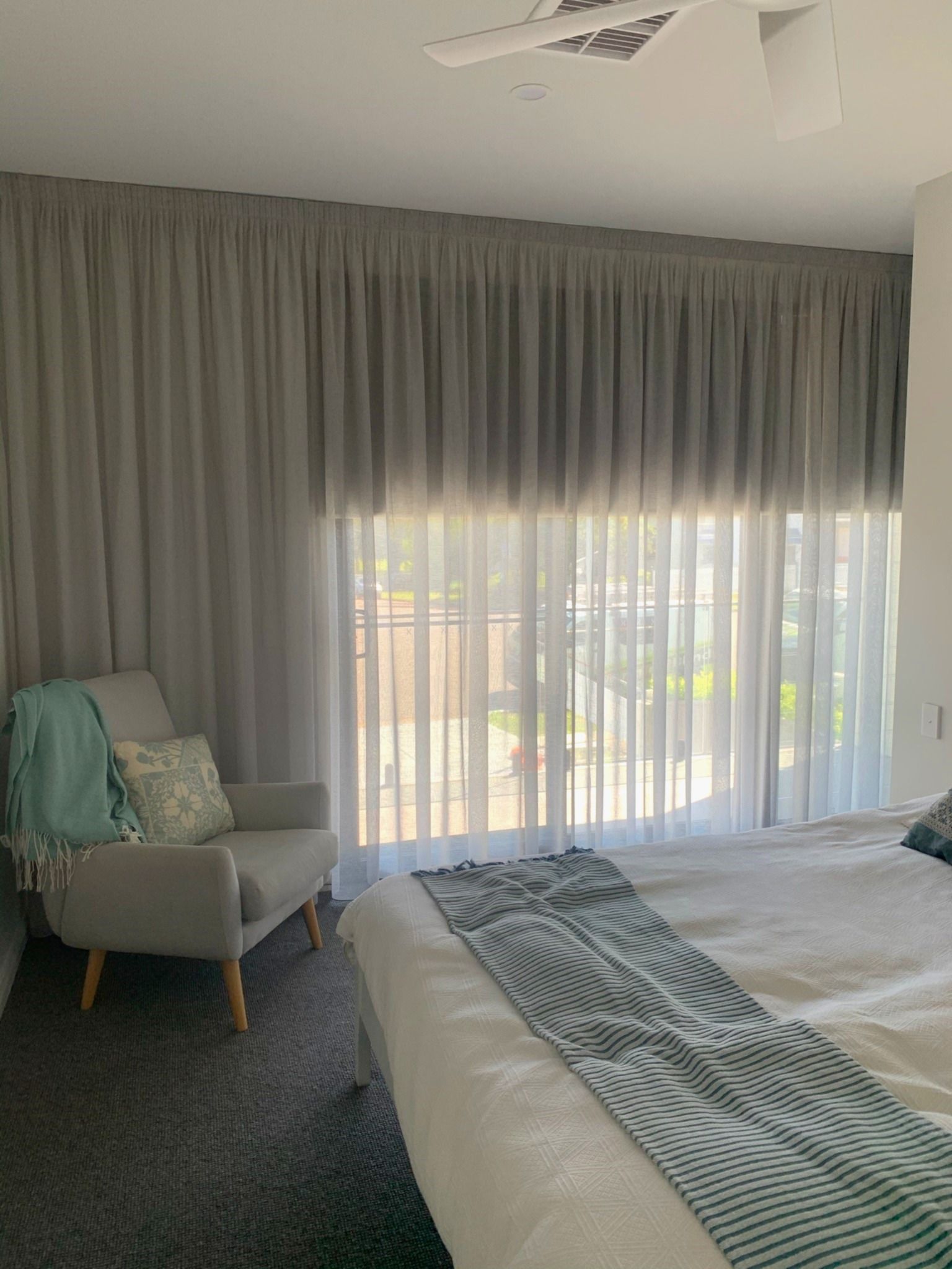 A bedroom with a bed and a view of the ocean — Winning Blinds in Cardiff, NSW