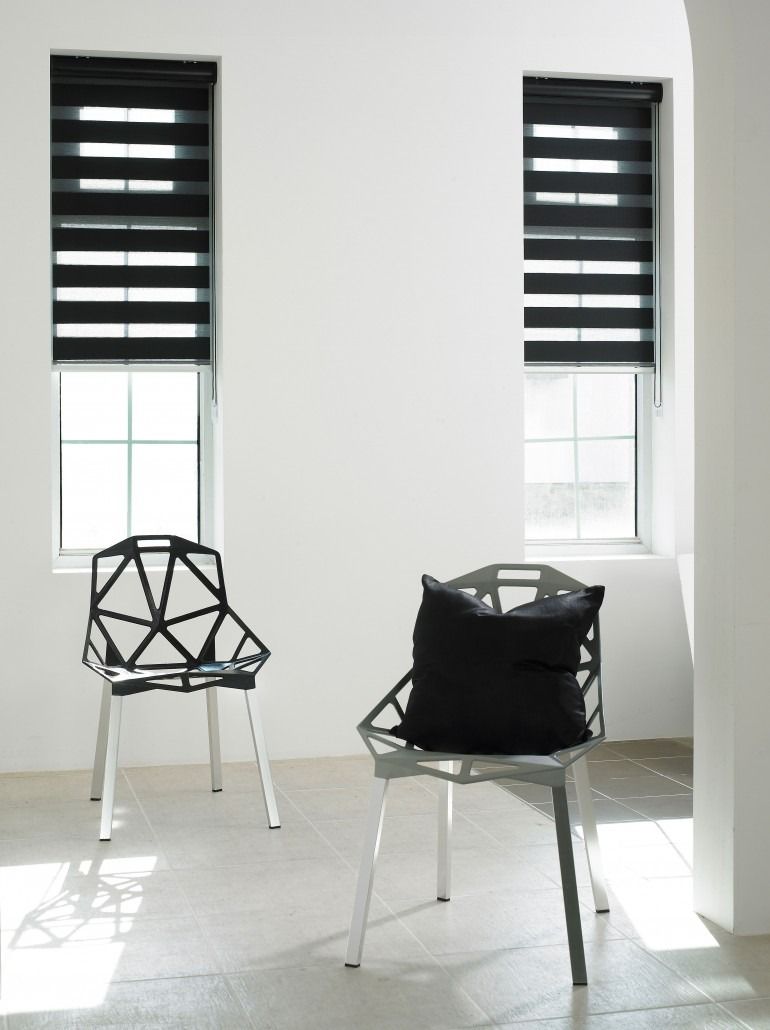 two chairs in a living room with windows and black lumen blinds in the background— Winning Blinds in Cardiff, NSW