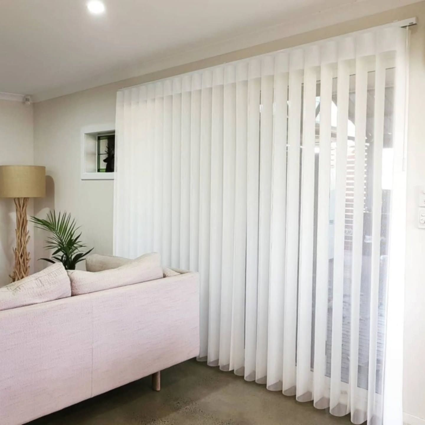 A bedroom with a bed and a window with white curtains  — Winning Blinds in Cardiff, NSW