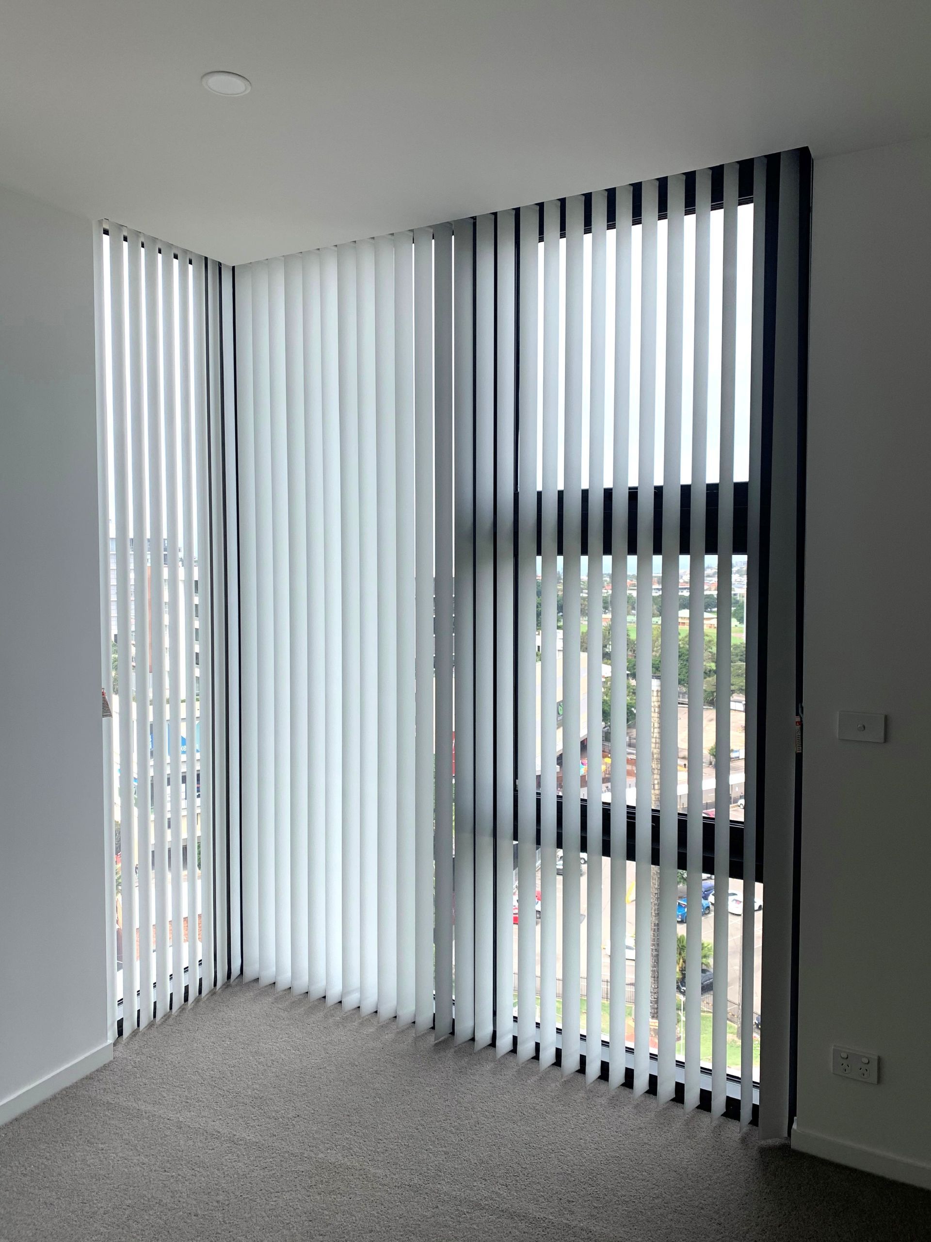 vertical blinds in a hotel building with grey carpet  — Winning Blinds in Cardiff, NSW