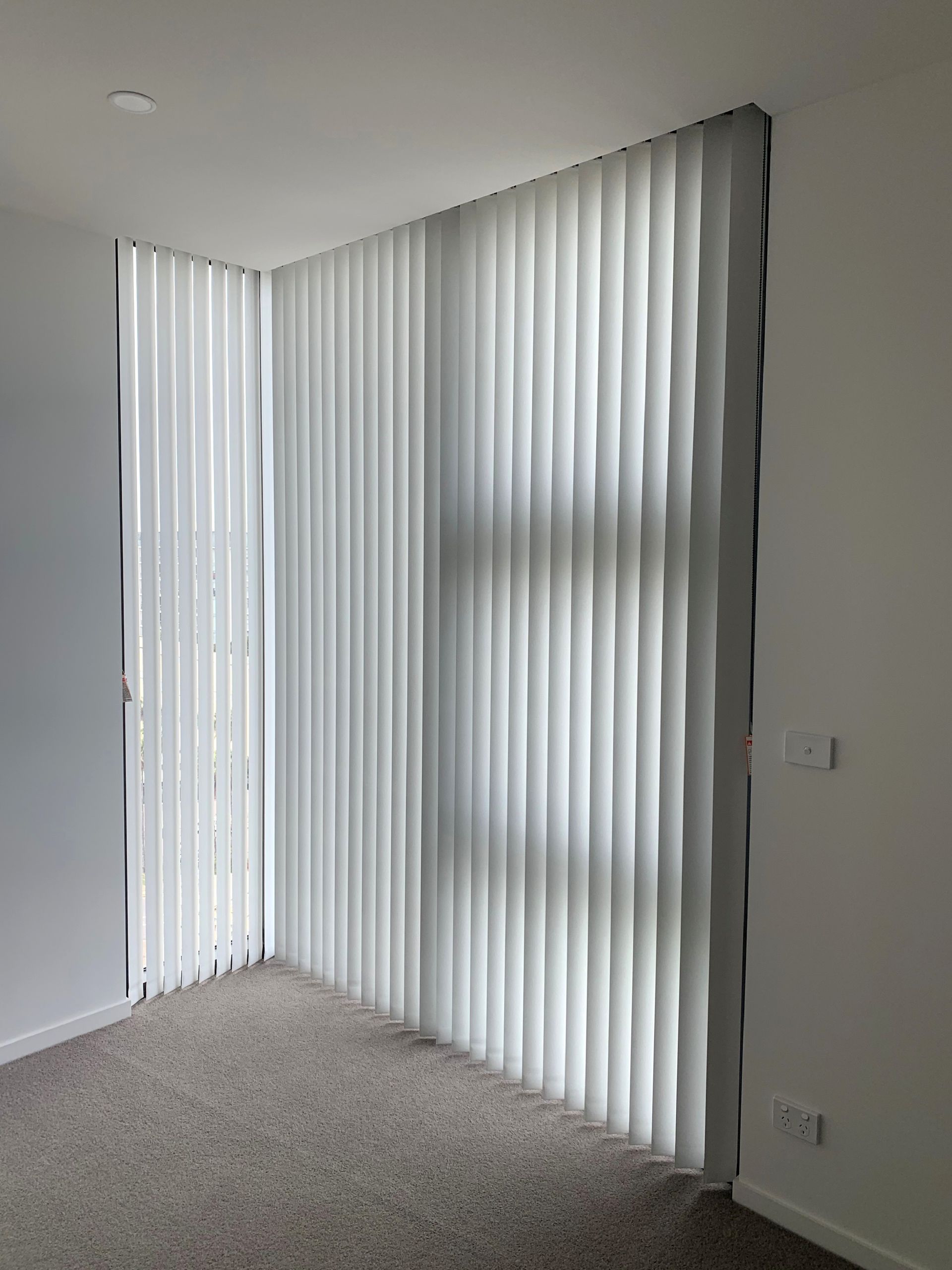 white vertical blinds in a hotel room— Winning Blinds in Cardiff, NSW