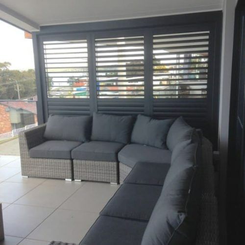A Living Room With a Couch and Shutters on the Windows — Winning Blinds in Cardiff, NSW