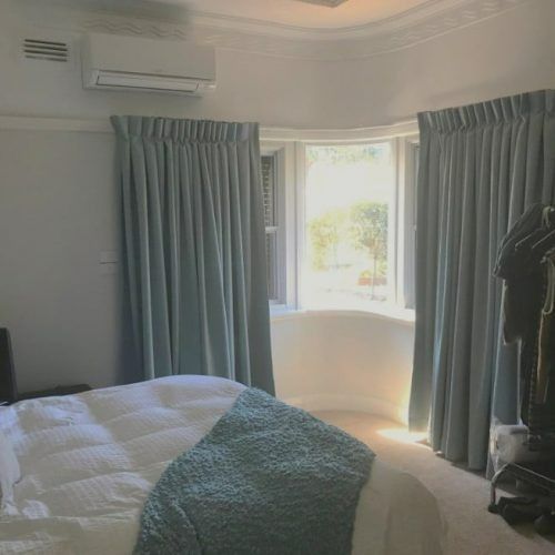 A Bedroom With a Bed , Curtains and a Window — Winning Blinds in Cardiff, NSW