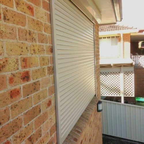 A Brick Wall With a White Shutter on It — Winning Blinds in Cardiff, NSW