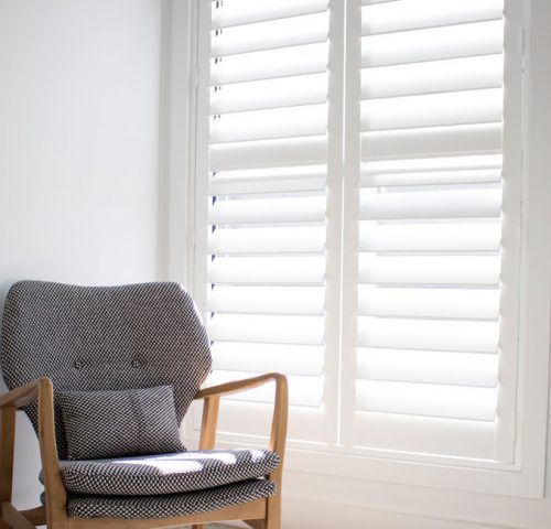Gray Patterned Armchair by a White Window With White Shutters — Winning Blinds in Cardiff, NSW