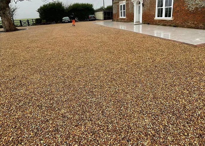 A gravel driveway in front of a brick house.
