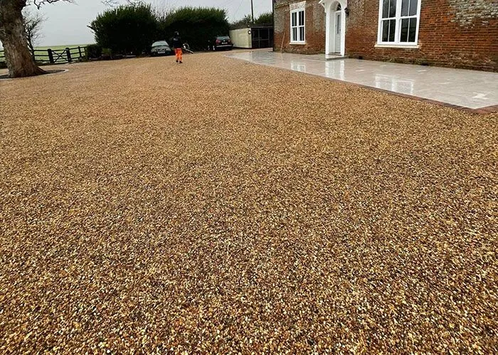 A gravel driveway in front of a brick house.