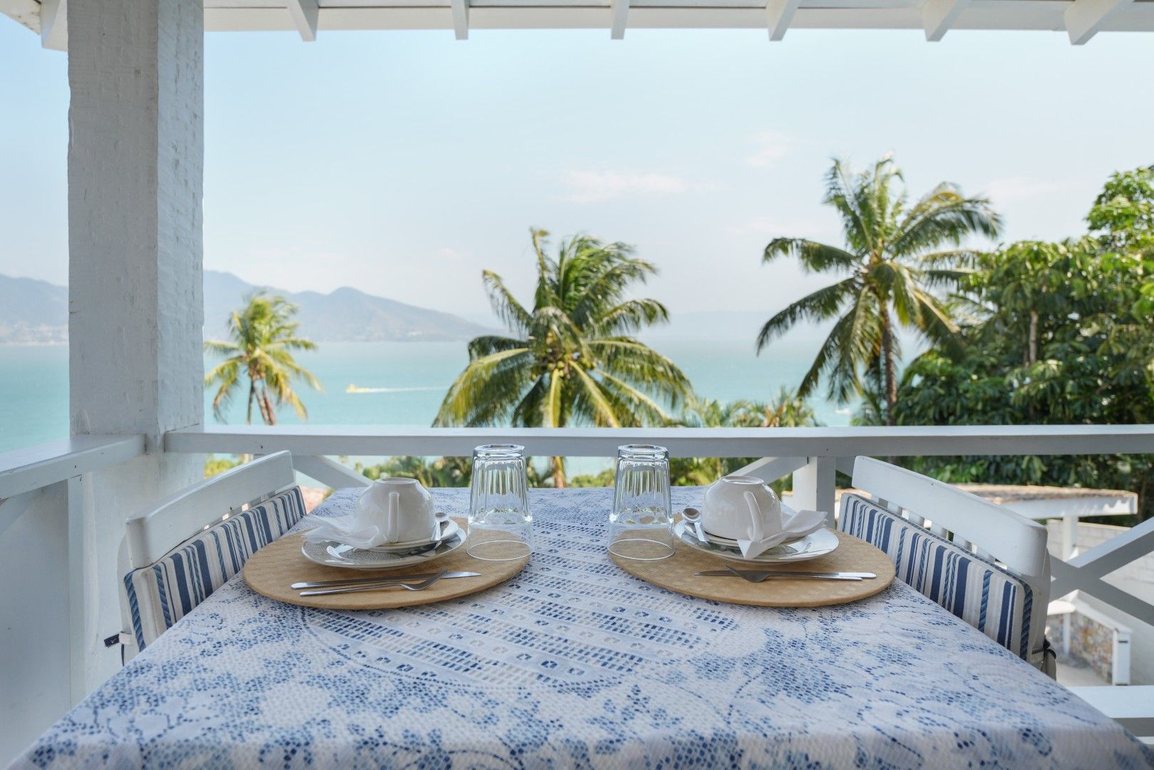 Prepare a mesa de café da manhã na varanda com vista para as palmeiras e o oceano.