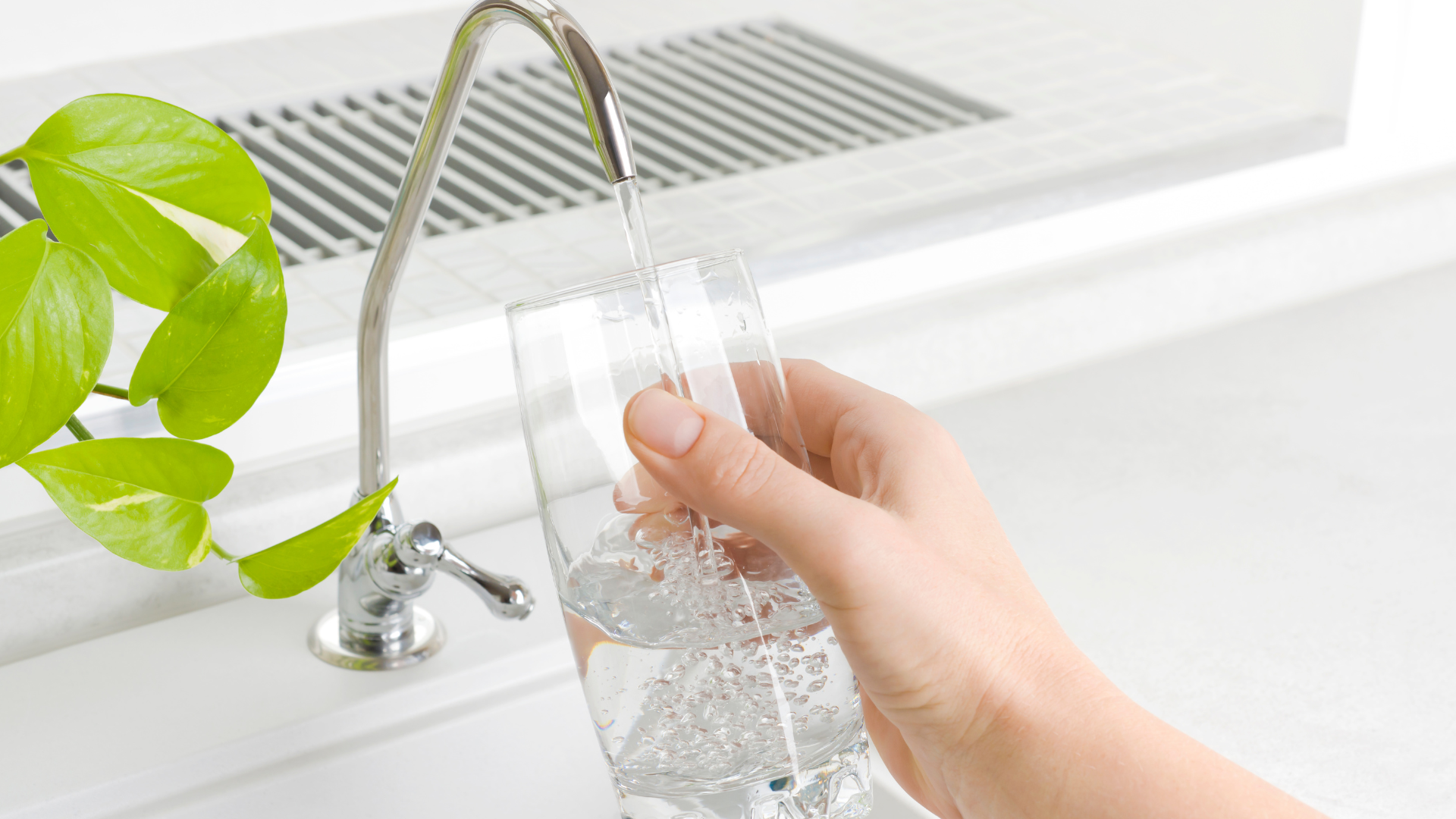 A person is pouring water into a glass from a faucet.