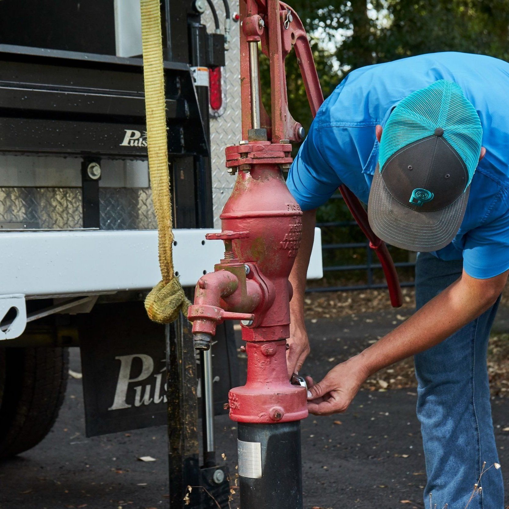 A man in a blue shirt is working on a red water pump