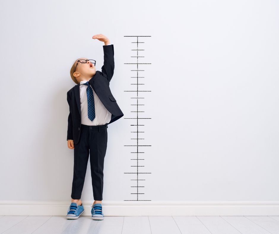 Child measuring height against a growth chart.