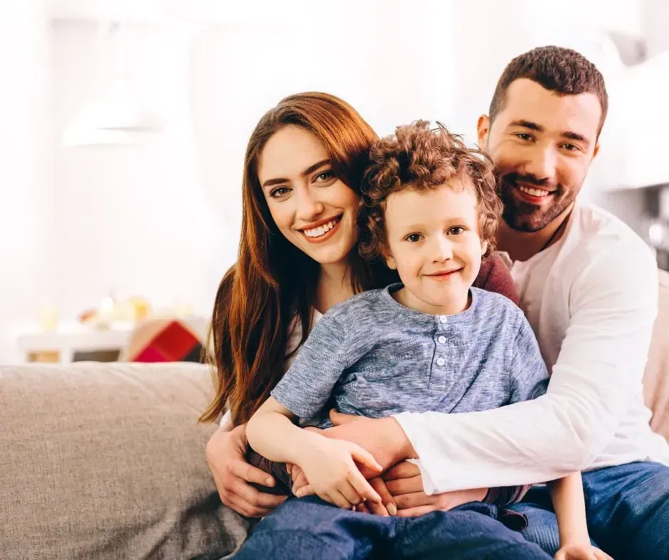 Parents hugging their young child at home.