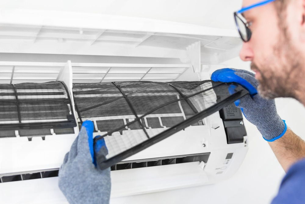 a man is cleaning the filter of an air conditioner .